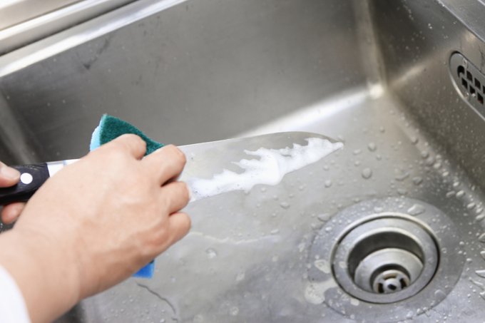 Washing a knife with soapy water.