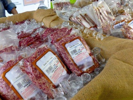 Packaged ground beef over ice at a farmers market.