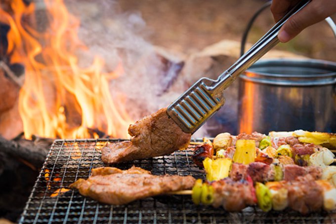 Grilling kabobs and chicken over a campfire.