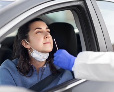 Female patient wearing a masks in her car about to get a covid-19 test