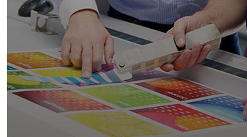 A person holding a color swatch up to a colorful calendar.