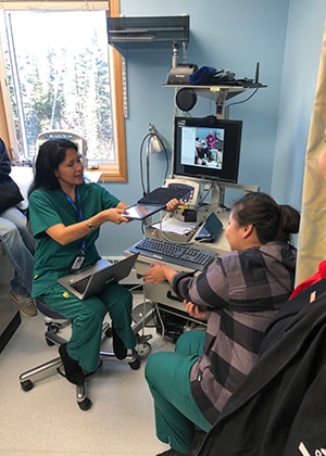 In Hughes, Alaska a community health aide use an online diagnostic tool to examine a patient with a rash and consult on treatment approaches through a two-way internet connection with a physician assistant and a pharmacist in Fairbanks.