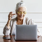 senior woman using laptop and drinking a glass of water