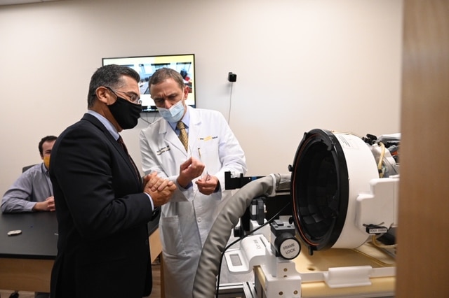 HHS Secretary Becerra speaking with a medical professional during a tour of a neuroscience institute.