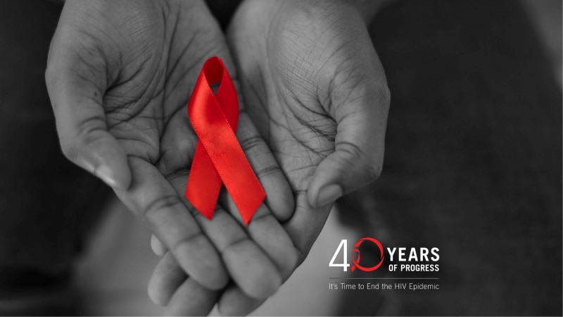 Hands holding red ribbon. 40 Years of Progress – It’s Time to End the HIV Epidemic