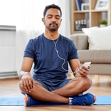 man on yoga mat with headphones in meditating